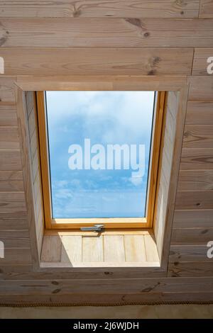 Finestra nella mansarda di una casa in legno. Finestra nel centro della casa. Il cielo è visibile dalla finestra Foto Stock