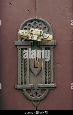 Antica maniglia della porta vintage sulla vecchia porta in legno. Elemento decorativo con foro per chiavetta in rame sulla superficie in legno resistente agli agenti atmosferici. Architettura in Slovacchia. Dettagli di Foto Stock