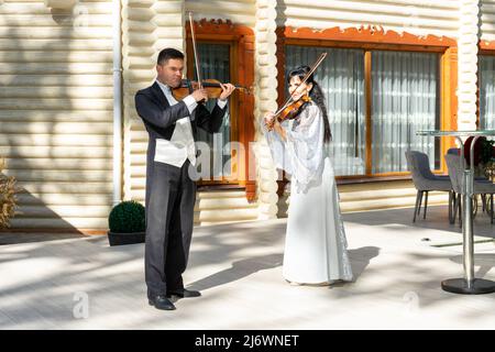 Duo di violinisti. Un uomo in un cappotto di coda e una donna in un abito da sera giocare il violino. Foto Stock