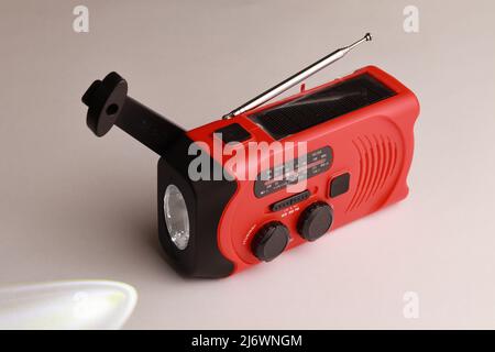 Piccola radio portatile rossa ricaricabile con pannelli solari o manualmente con una manovella. Torcia inclusa Foto Stock