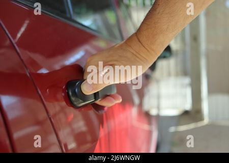 Un uomo apre la porta posteriore della sua auto Foto Stock