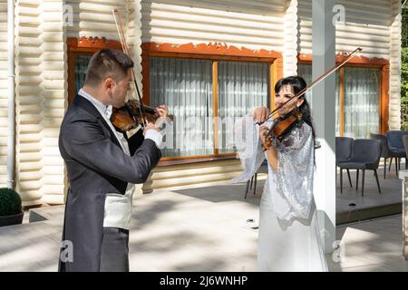 Duo di violinisti. Un uomo in un cappotto di coda e una donna in un abito da sera giocare il violino. Foto Stock