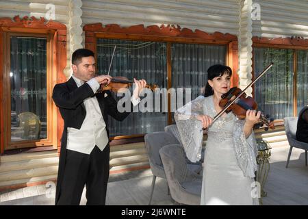 Duo di violinisti. Un uomo in un cappotto di coda e una donna in un abito da sera giocare il violino. Foto Stock