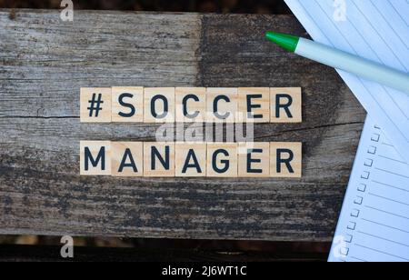 Blocchi giocattolo in legno con il testo Soccer Manager su di esso con penna e carta sullo sfondo. Scatto perfetto per manager, manager e blogger di calcio. Foto Stock