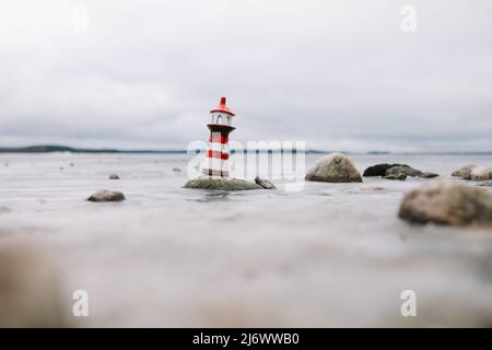 Mare d'inverno ghiacciato con faro decorativo. Stile di vita nautico. Inverno, Mare, Viaggi, avventura, vacanze e vacanza concetto. Viaggia nel 2021. Foto Stock