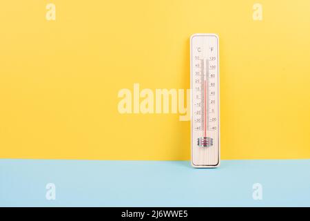 Termometro su sfondo giallo e blu, misura la temperatura, le previsioni del tempo, il riscaldamento globale e la discussione ambientale, i mari estivi Foto Stock