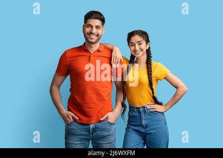 Ritratto di attraente giovane uomo arabo e donna che posano su sfondo blu, Foto Stock
