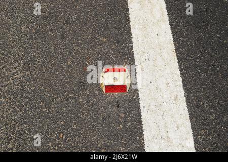Prigioniero di Metal Road con catarifrangente rosso su strada asfaltata con linea di demarcazione della corsia dipinta di bianco come divisore sulla strada statale in India Foto Stock