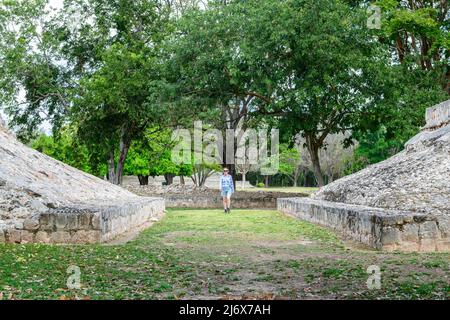 Una donna turistica che esplora le rovine del campo da ballo dell'antica città maya di Edzna - famoso sito archeologico vicino a Campeche, penisola dello Yucatan, Messico Foto Stock