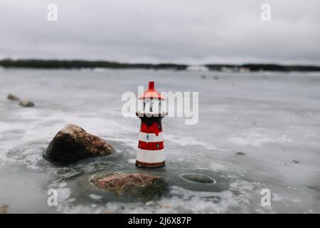 Mare d'inverno ghiacciato con faro decorativo. Stile di vita nautico. Inverno, Mare, Viaggi, avventura, vacanze e vacanza concetto. Viaggia nel 2021. Foto Stock