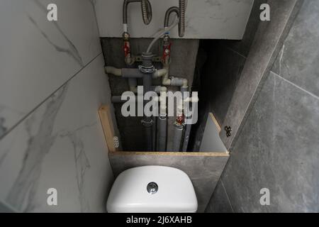 Tubi dell'acqua, valvole e manometri all'interno della casa, sistema con pompe elettriche e riscaldatori. Pipeline in metallo per caldaie domestiche, tubi caldi e freddi in servizio Foto Stock