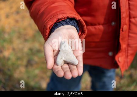 Le mani del bambino tengono una pietra a forma di cuore Foto Stock