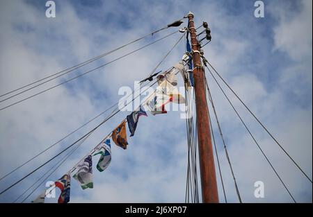 Carolinensiel, Germania - 13 agosto 2021: Albero di una vecchia barca a vela in legno con pennanti colorati contro il cielo blu durante l'evento Wattensail 2021. Foto Stock