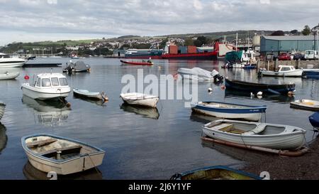 Piccole barche da diporto ormeggiate a Back Beach, Teignmouth, Devon, Inghilterra, Regno Unito, con tre navi in mare ormeggiate ai moli sullo sfondo. Foto Stock