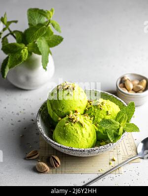 Gustoso gelato al pistacchio con menta guarnito con pistacchi schiacciati su sfondo testurizzato Foto Stock