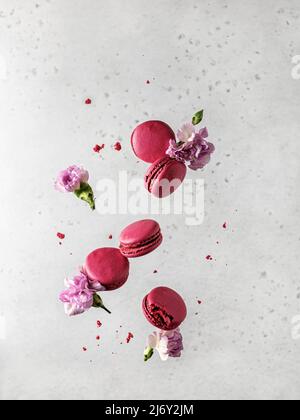 Macaron rosa levitating e fiori. Primavera, concetto di giorno femminile Foto Stock