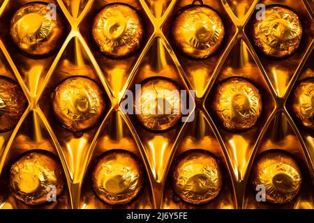 Primo piano di bononi di cioccolato avvolti in lamina d'oro nella loro scatola Foto Stock