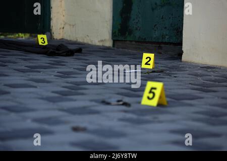 Prova con indicatore CSI giallo per la numerazione delle prove sul cortile interno in serata. Concetto del processo di indagine sulla scena del crimine Foto Stock