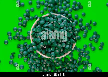 Spirulina alghe Tablets.Spirulina pills in a round ciotola.Green spirulina compresse su sfondo verde. Vitamine e supplementi dietetici Foto Stock