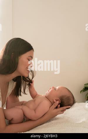 Latino giovane madre giocare felice con il bambino sul letto a casa Foto Stock