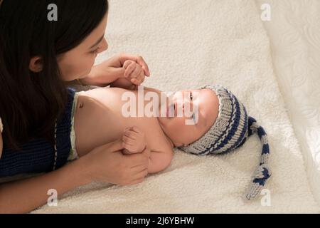 Latino giovane madre giocare felice con le mani del bambino sul letto a casa Foto Stock