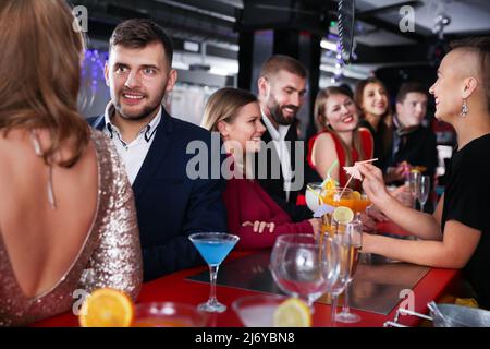 Colleghi cordiali che si festeggiano al bar e tostano bevande Foto Stock