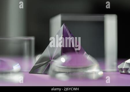 Luce rifrangente a prisma di cristallo, cristalli magici e piramide, sfera e cubo su sfondo viola. Pratica di cristallo di guarigione spirituale. Feng Shui, bravo Foto Stock