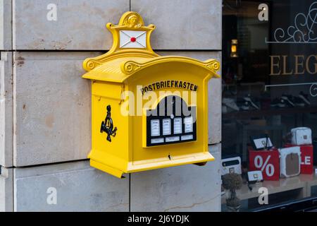 Vecchia casella postale gialla della posta tedesca. Una scatola di lettere per inviare carte e lettere su un muro di pietra arenaria. Foto Stock