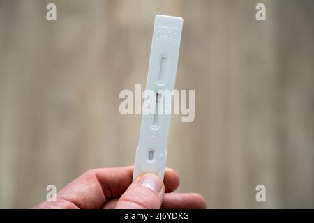 Tenendo un test della saliva dell'antigene Covid-19 con esito negativo. Campione di plastica per un rapido controllo del coronavirus da Hotten. Punto di vista. Foto Stock