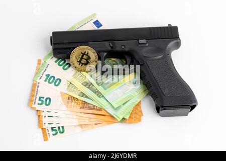 Banconote da pistola, Bitcoin e euro su sfondo bianco. Simboli di criminalità nel mondo reale e darknet. Denaro contante e BTC utilizzati come pagamento. Foto Stock
