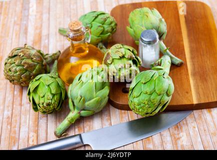 Carciofi verdi, olio e sale a tavola Foto Stock