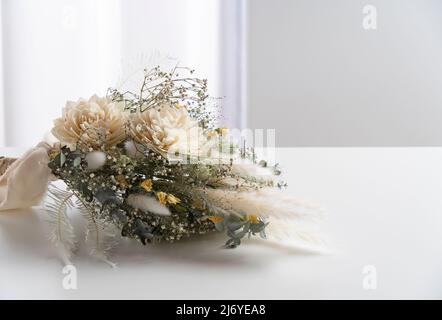 Bouquet di fiori secchi posto su un tavolo bianco. Concetto di matrimonio e celebrazione. Foto Stock