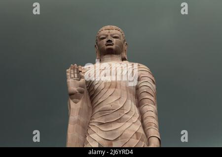 Una statua in pietra arenaria alta 80 piedi del Buddha in piedi a Sarnath alla periferia di Varanasi, Uttar Pradesh, India. Costruita dal 1997 al 2011, la statua fu il risultato di uno sforzo congiunto tra Thailandia e India. Foto Stock