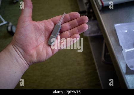 in una mano vi è un registratore di eventi impiantabile per registrare problemi cardiaci Foto Stock