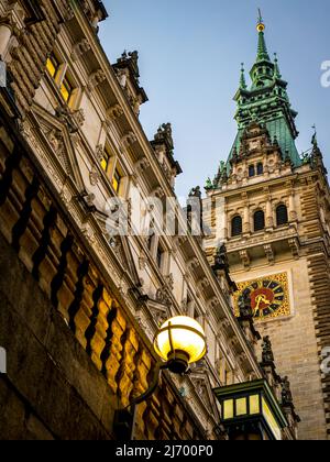 foto verticale in prospettiva ad angolo basso dell'impressionante municipio in stile neo-rinascimentale nel quartiere del centro di amburgo illuminato. Foto Stock