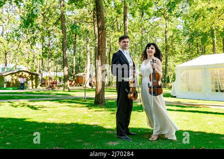 duo di violinisti con violini in mano nel parco. Foto Stock