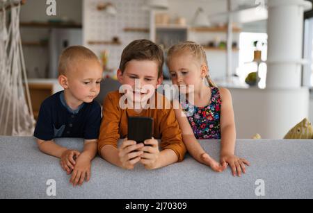 Concetto di smartphone per bambini con tecnologia infantile. Bambini piccoli felici che giocano sul telefono cellulare Foto Stock