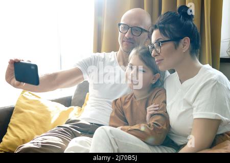 Famiglia felice che porta il selfie con lo smartphone a casa Foto Stock