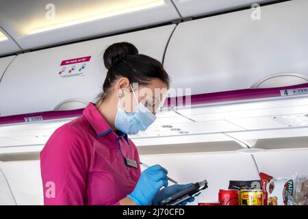 BUDAPEST - FEB 01: Stewardess in una maschera protettiva su un bordo di un aeroplano durante il convivio - 19 pandemia a Budapest, Febbraio 01. 2022 in Ungheria Foto Stock