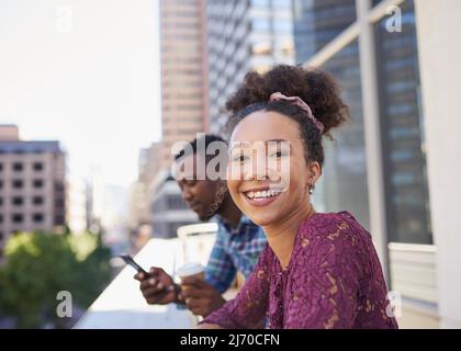 Una giovane donna multietnica sorride durante una pausa di lavoro su un balcone cittadino Foto Stock