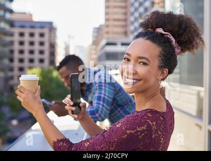 Una giovane donna scatta una foto del suo caffè sul balcone con vista sulla città Foto Stock