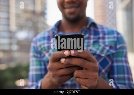 Un primo piano delle mani che testano sul cellulare con sfondo cittadino Foto Stock