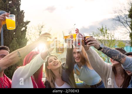 gruppo di amici che festeggiano con un brindisi al tramonto nel parco Foto Stock