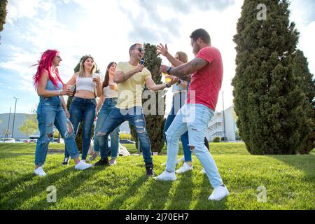 gruppo di amici che cantano e ballano in una festa all'aperto Foto Stock