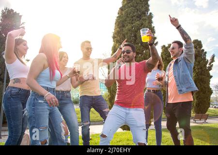 giovane che canta con il microfono con il suo gruppo di amiche per celebrare una festa all'aperto Foto Stock