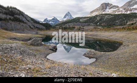 Prominente picco che si riflette nel lago alpino in una piccola valle, il Monte Assiniboine Pr. Park, Canada Foto Stock