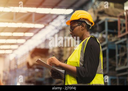 Ingegnere nero donna lavoratore, professionale donna afican lavoro di manutenzione meccanica in fabbrica di controllo magazzino inventario in magazzino. Foto Stock