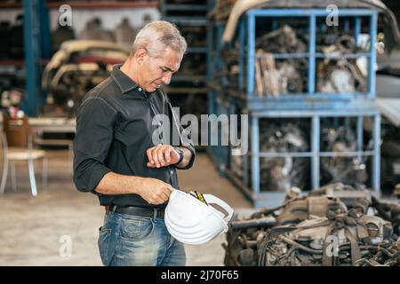 ingegnere lavoratore maschio cercando orologio da polso per stress preoccupazione con lavoro tardi apointment concetto tempo Foto Stock