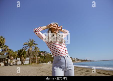 Donna fiduciosa con volto felice in posa sul mare Foto Stock