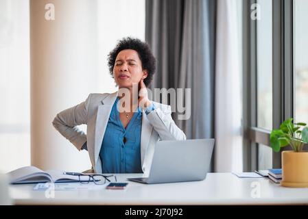 Donna d'affari che soffre di dolore al collo e mal di schiena, professionista femminile è in problema mentre si lavora sul laptop alla scrivania, è stanca e overworking in Foto Stock